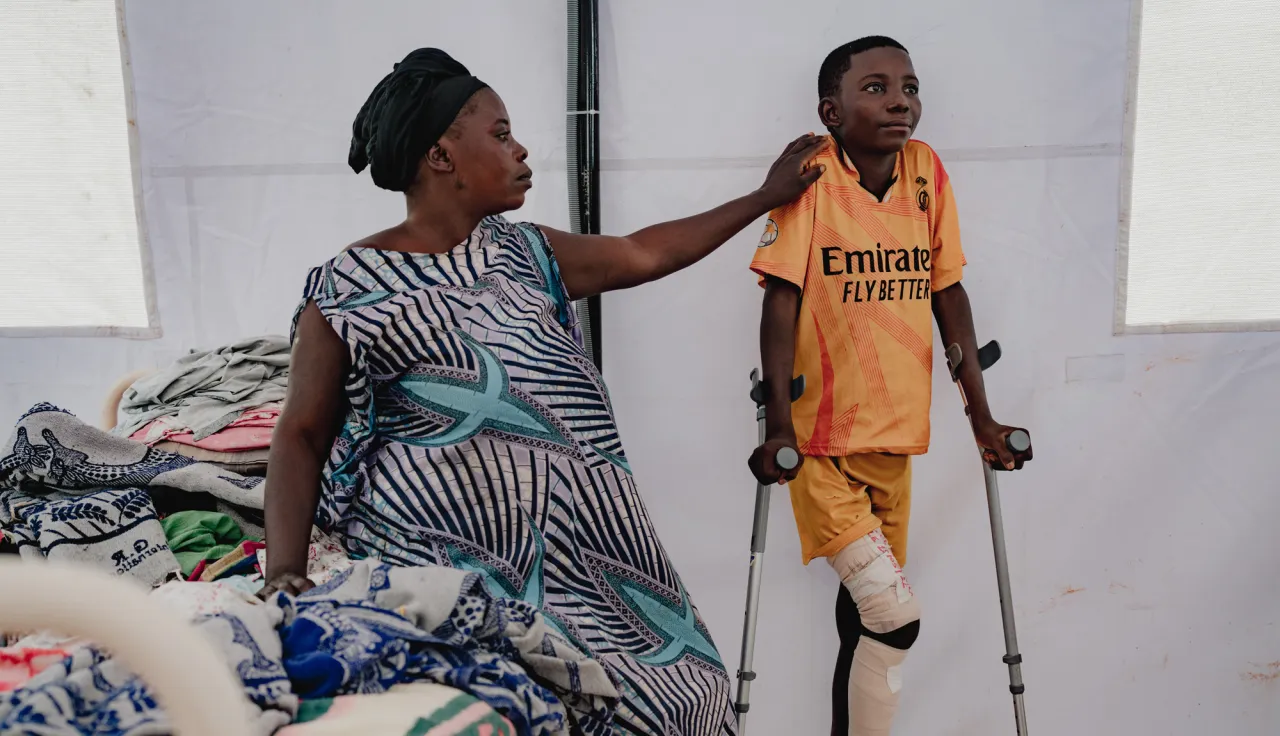 Adela Yang and her son Ebwela Liko at Fizi general hospital.  Adela’s son is 14 years old, and was hit by a bullet in the leg whilst he was sheltering at home from fighting in his home village of Kaguli. “We were hiding at home, but he stood up to run away, and so was hurt by a bullet. Others in the village, including his teacher came and helped carry him to the health centre. It was 5 kilometres away. We stayed there for 1 week while they stabilised him. A CICR ambulance brought him to the