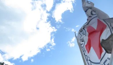 Bandera del CICR ondeando con el cielo y las nubes en el fondo
